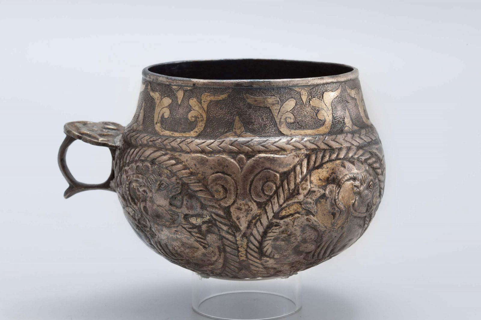 Spherical cup with ring handle. The body of the cup has roundels with goals and a vegetal motif at the rim.