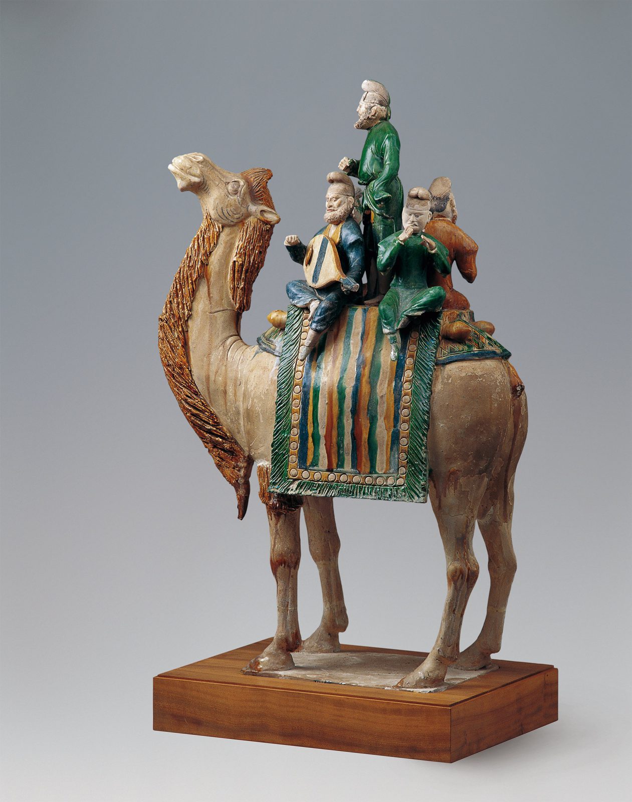 Four musicians sit on a camel and play.